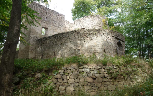 Man-made Bolczów Castle stone ruins among trees, weathered fortress walls and mossy terraces, shown as a 2K Quad HD PC desktop wallpaper/background.