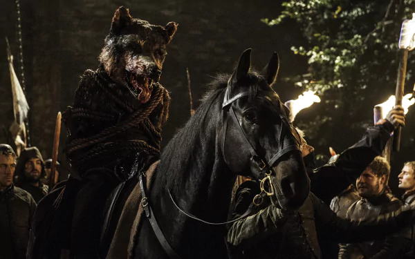 A dramatic scene from Game of Thrones features a character in a wolf mask riding a black horse, surrounded by a group holding torches in a dark forest setting.