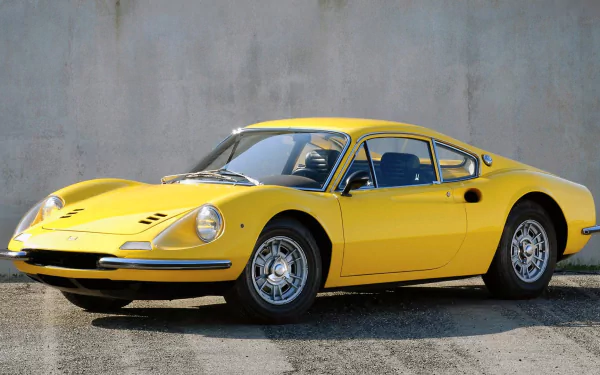 HD desktop wallpaper featuring a yellow Ferrari Dino 206 GT parked against a plain concrete wall, showcasing its classic sports car design.