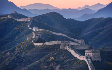 A stunning HD wallpaper of the Great Wall of China, showcasing its sweeping structure across mountainous terrain at sunset, highlighting the majesty of this man-made wonder.