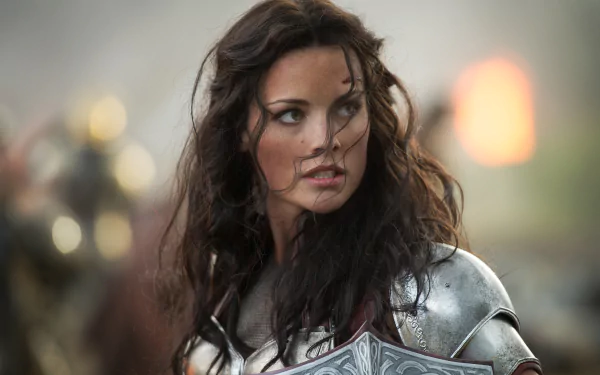 A dramatic scene from Thor: The Dark World, featuring a woman in silver armor, capturing the essence of battle and determination in this stunning 4K Ultra HD wallpaper.