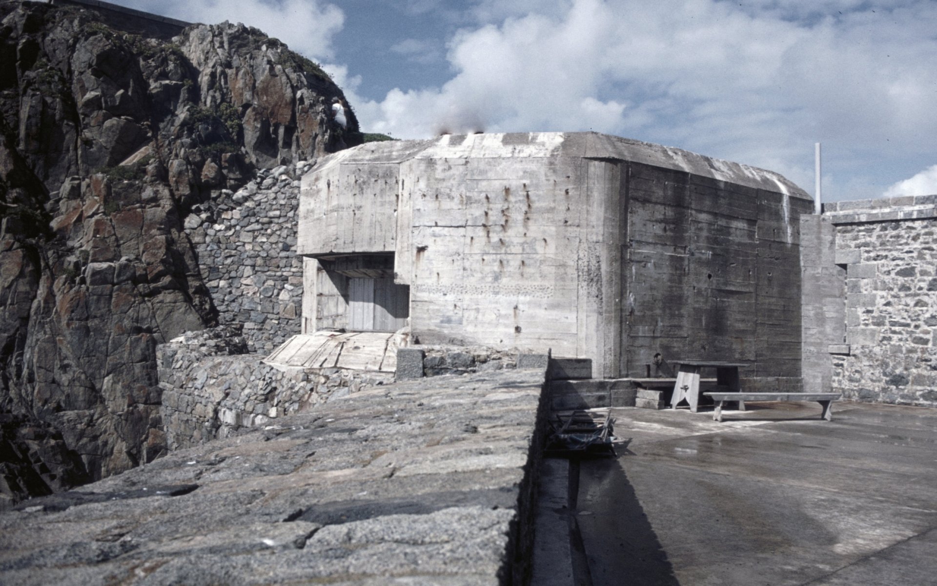 A concrete structure at Fort Clonque, surrounded by rocky terrain and a dramatic sky, captured in high definition as a desktop wallpaper and background.