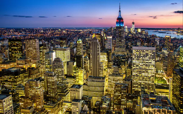 HD desktop wallpaper showcasing a vibrant nighttime man-made New York City skyline with illuminated skyscrapers and the Empire State Building under a colorful twilight sky.