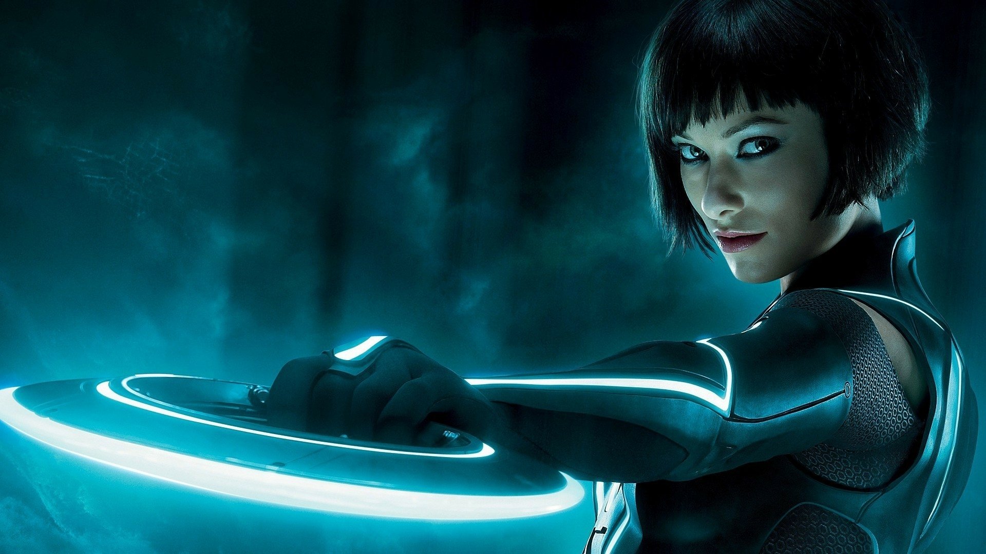 HD PC desktop wallpaper/background from the movie TRON: Legacy — a glowing-suited figure holding a lit disc against a neon-blue digital backdrop.