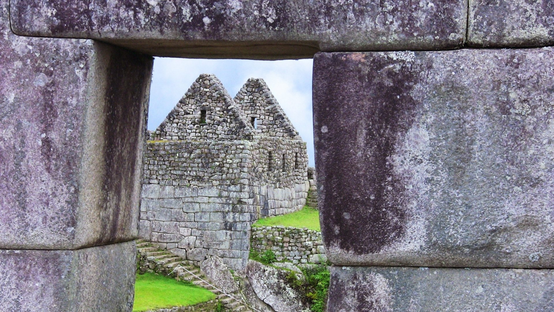 HD PC desktop wallpaper featuring the man-made stone structures of Machu Picchu framed through an ancient stone window.