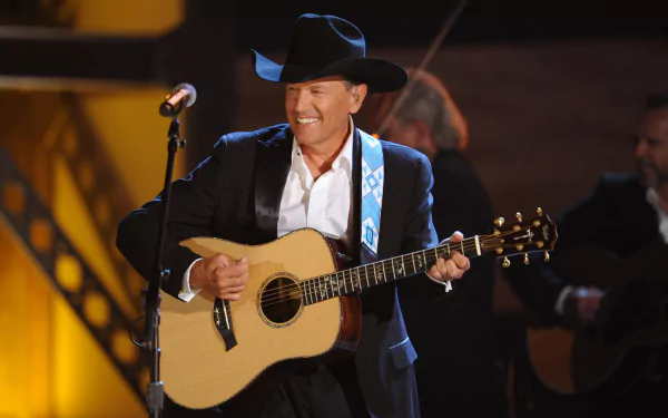 George Strait performing live with an acoustic guitar, captured in a vibrant 4K Ultra HD wallpaper showcasing his iconic cowboy hat and smile.