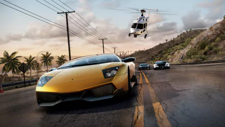 HD PC desktop wallpaper from the video game Need For Speed: Hot Pursuit, featuring a yellow sports car racing on a coastal road with a police helicopter in pursuit.