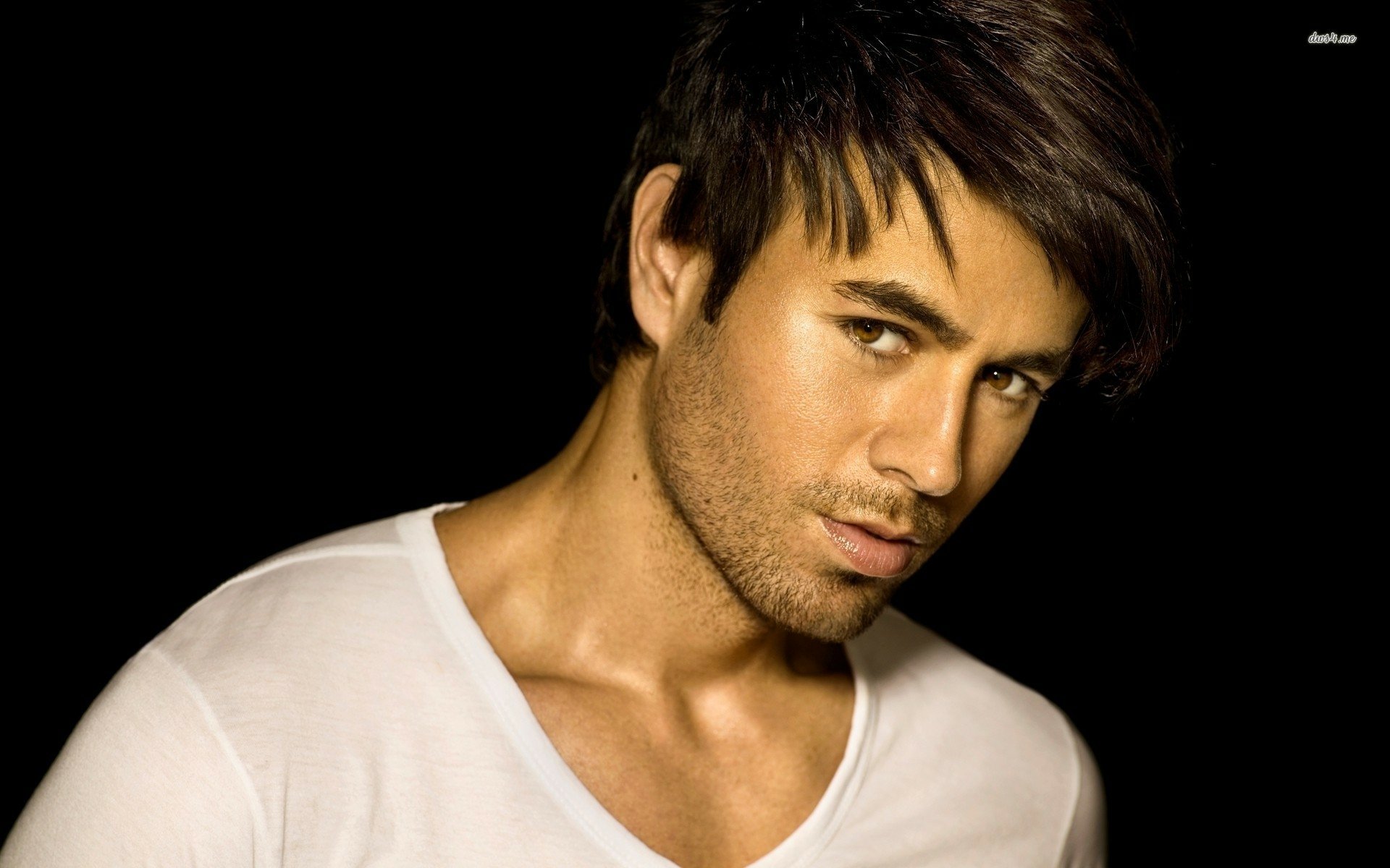 A high-definition desktop wallpaper featuring Enrique Iglesias, showcasing his striking expression and style against a dark background, capturing the essence of music and charisma.