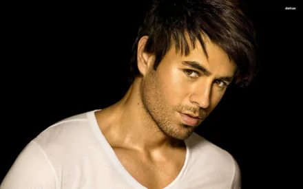 A high-definition desktop wallpaper featuring Enrique Iglesias, showcasing his striking expression and style against a dark background, capturing the essence of music and charisma.