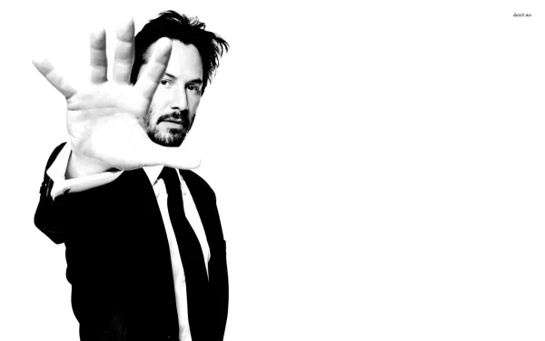 HD PC desktop wallpaper featuring celebrity Keanu Reeves in a black suit with his hand extended toward the camera against a white background.