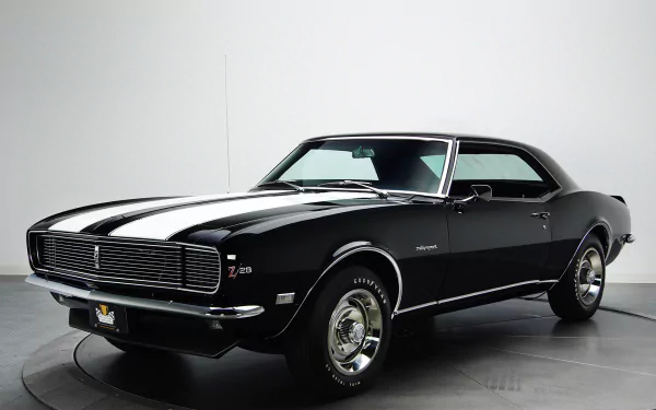 HD desktop wallpaper featuring a black Chevrolet Camaro Z28 RS with white racing stripes against a clean, minimal background.