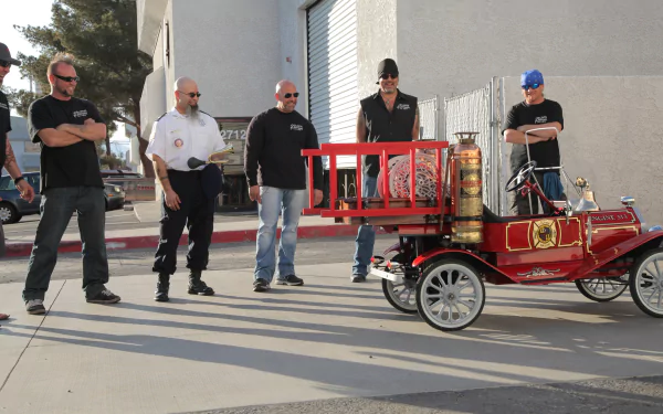 HD PC desktop wallpaper featuring cast members from the TV show Counting Cars examining a vintage red fire truck.