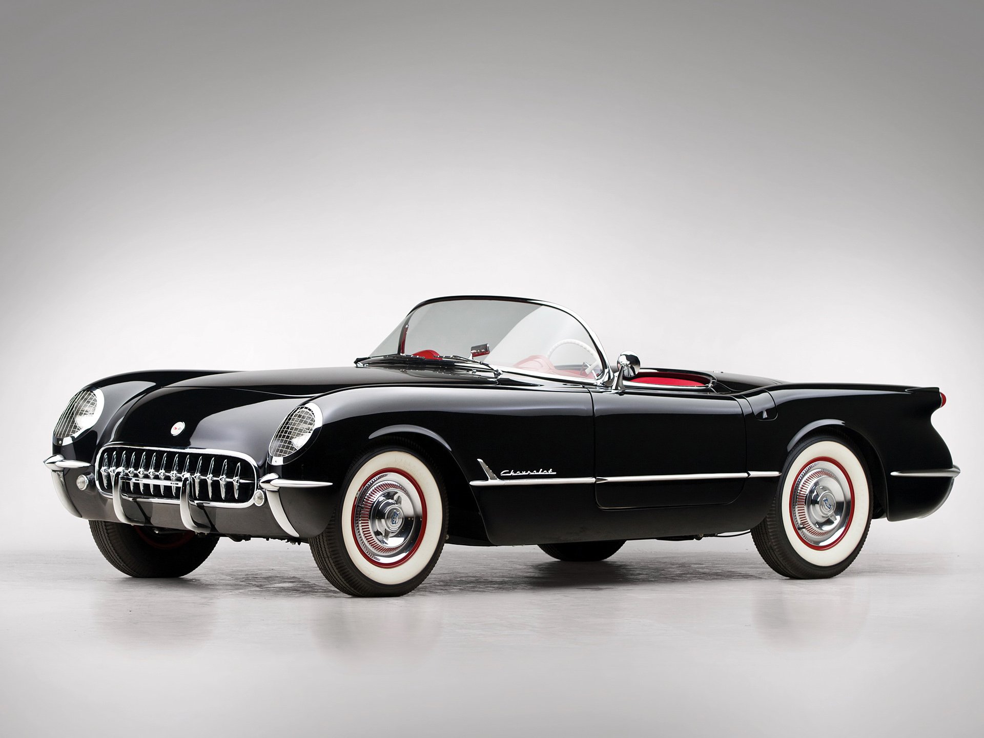 HD PC desktop wallpaper of a classic black Chevrolet Corvette (C1) convertible showcasing its sleek vintage design against a plain background.
