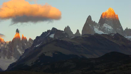 Nature HD PC desktop wallpaper/background: Mount Fitz Roy at sunrise — jagged granite peaks glowing orange with alpenglow, low cloud and shadowed foothills.