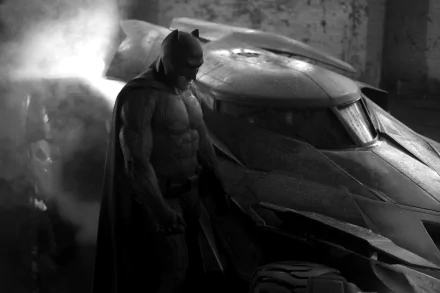 Batman stands next to the Batmobile in a dark, smoky setting from Batman V Superman: Dawn Of Justice. This HD desktop wallpaper captures the moody atmosphere and iconic characters from the movie.