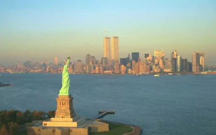 HD PC desktop wallpaper of New York harbor: Statue of Liberty in foreground with the Twin Towers on the man-made skyline at dawn.