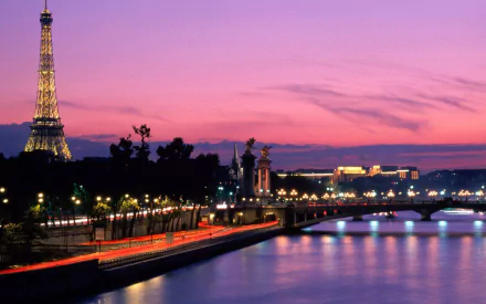 A stunning HD desktop wallpaper showcasing the Eiffel Tower in Paris at dusk, framed by a vibrant sky and the serene river reflecting the warm lights of the city.