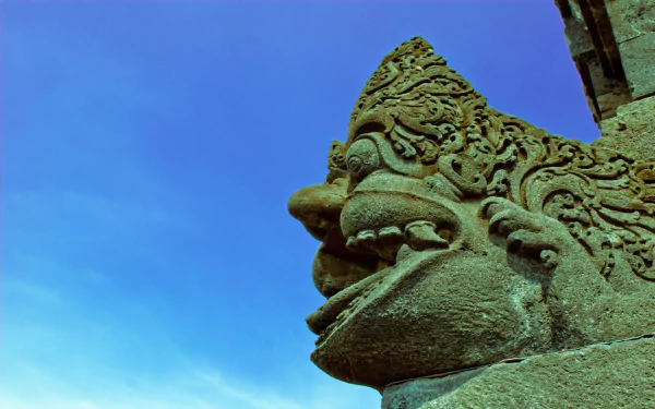 Religious stone guardian detail at Borobudur temple against a vivid blue sky — HD PC desktop wallpaper and background.