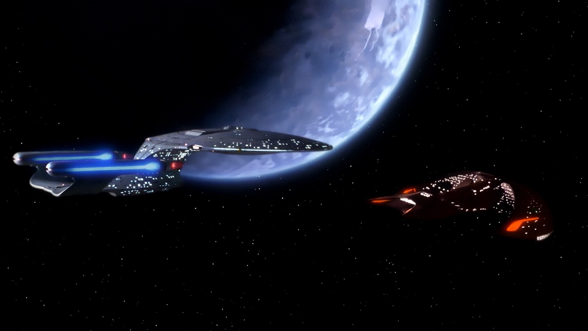 HD PC desktop wallpaper from the TV show Star Trek: The Next Generation — the USS Enterprise‑D nears a blue planet as a Klingon ship waits against a starfield.