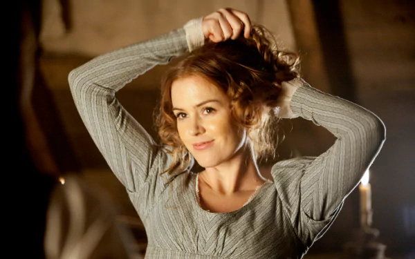 Isla Fisher, the Australian actress, poses gracefully with a playful expression, showcasing her curly hair in this captivating HD wallpaper background.