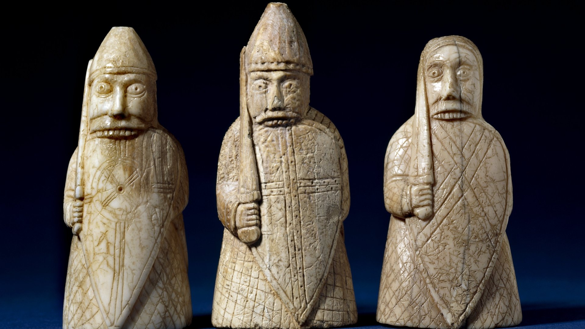 Close-up of three carved man-made chess pieces with intricate details, presented as an HD PC desktop wallpaper and background against a dark backdrop.