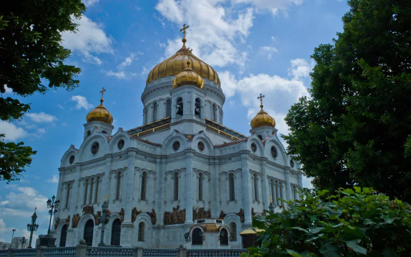 HD PC desktop wallpaper featuring the Cathedral of Christ the Saviour with its golden domes under a bright blue sky framed by greenery.