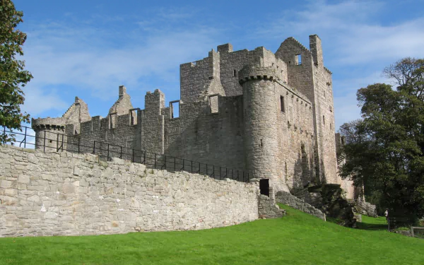 HD desktop wallpaper showcasing the man-made Craigmillar Castle with stone walls and towers set against a blue sky and green lawn.