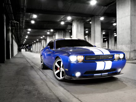 A blue Dodge Challenger SRT8 with white racing stripes parked in a dimly lit underground garage, showcased in a high-definition desktop wallpaper.