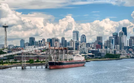 HD desktop wallpaper of Seattle's man-made skyline with the iconic Space Needle and a docked ship under a partly cloudy sky.