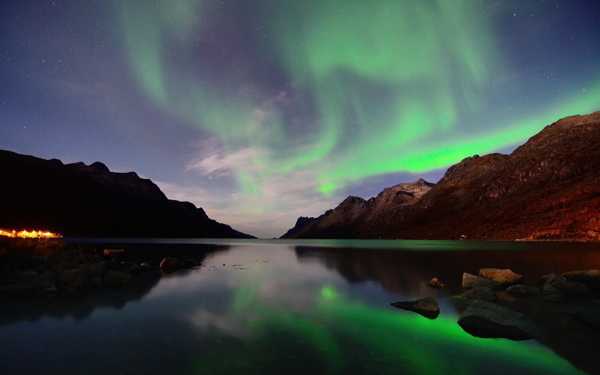 HD PC desktop wallpaper showcasing vibrant green aurora borealis dancing over a serene lake surrounded by dark mountains under a starry night sky.