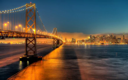 A stunning view of the Bay Bridge illuminated at night, reflected in the river, with the San Francisco skyline glowing in the background. A captivating urban landscape in California.