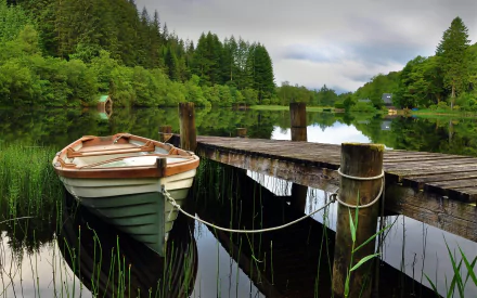 HD PC desktop wallpaper showing a small boat moored to a wooden dock on a calm river surrounded by lush green trees.