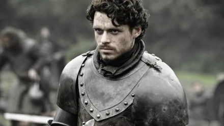 Richard Madden as Robb Stark from Game of Thrones, portrayed in a dramatic moment wearing armor, set against a background of blurred greenery. 4K Ultra HD wallpaper.