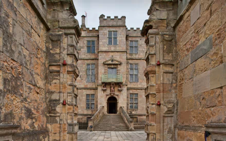 HD PC wallpaper of Bolsover Castle, featuring detailed stone architecture and an arched entrance framed by weathered walls.