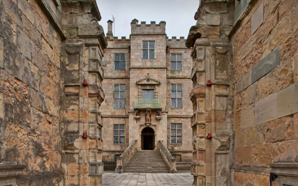 HD PC wallpaper of Bolsover Castle, featuring detailed stone architecture and an arched entrance framed by weathered walls.