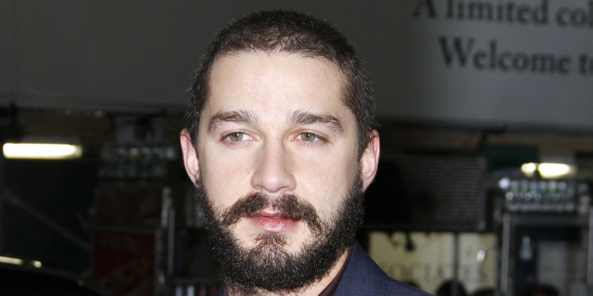 HD desktop wallpaper featuring a portrait of a bearded Shia Labeouf with a focused gaze.