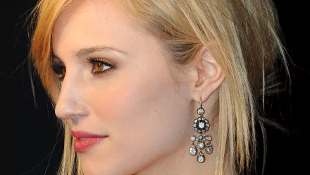 Close-up HD desktop wallpaper of American actress Dianna Agron, showcasing her profile with elegant earrings and subtle makeup against a dark background.