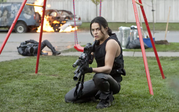HD PC desktop wallpaper from the movie Resident Evil: Retribution featuring a woman in tactical gear holding a rifle in a playground with burning cars in the background.