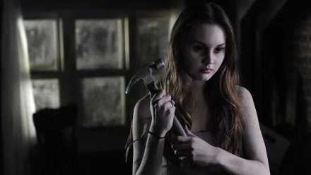 Liana Liberato in a dark, moody scene from the movie *Haunt*, holding a hammer, presented as a 4K Ultra HD PC desktop wallpaper background.