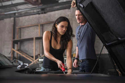 Michelle Rodriguez as Letty Ortiz works on a car alongside a mechanic in this HD wallpaper from Fast & Furious 6, showcasing action and teamwork in a dynamic setting.