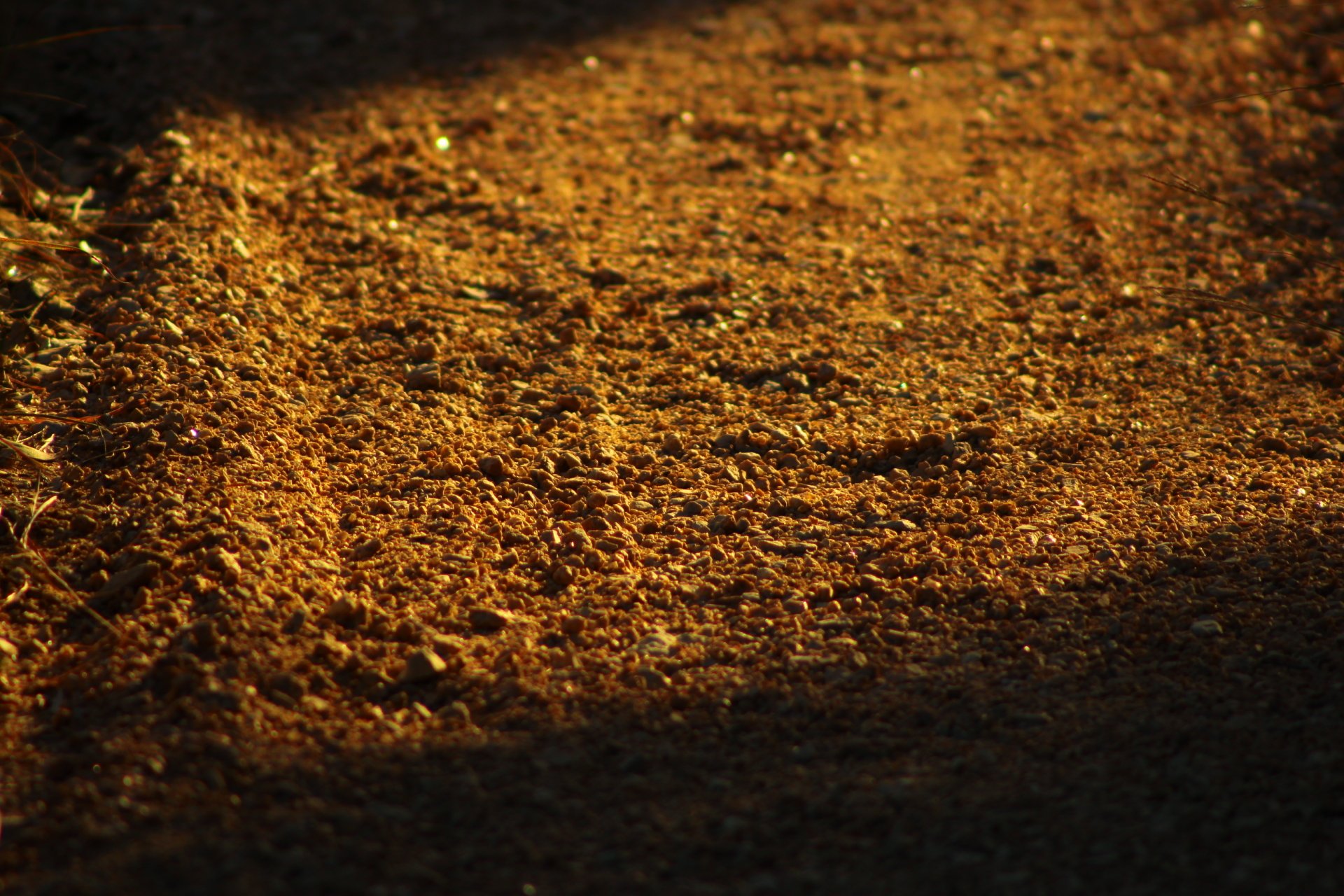 Close-up of a man-made road surface covered with small pebbles and stones, captured in high-definition detail for a PC desktop wallpaper background.
