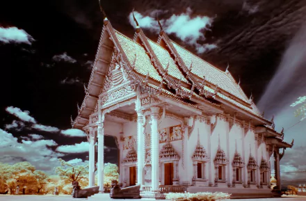 Ornate Thai religious temple with white columns and gabled roof under a dramatic sky — 2K Quad HD PC desktop wallpaper and background
