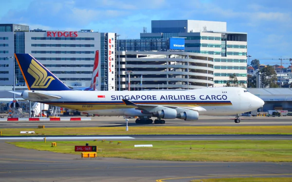 A Singapore Airlines Cargo Boeing 747 taxis at Sydney Airport, surrounded by modern buildings, showcasing the dynamic air transport scene. High-definition desktop wallpaper.