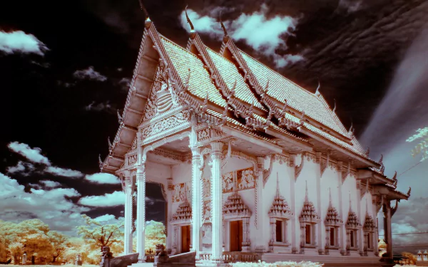 Ornate Thai religious temple with white columns and gabled roof under a dramatic sky — 2K Quad HD PC desktop wallpaper and background