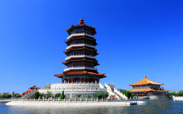 HD desktop wallpaper of a traditional Chinese religious temple and pagoda set against a clear blue sky and calm water, showcasing classic architectural details.