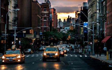 A vibrant New York street scene at dusk, featuring golden taxis and illuminated buildings, captured in an HD wallpaper that showcases the dynamic energy of the city.