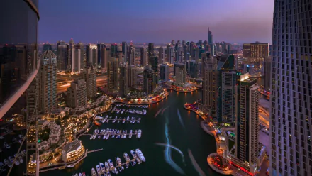 A stunning HD wallpaper showcasing the vibrant skyline of Dubai at dusk, featuring tall skyscrapers, a shimmering marina, and a glowing waterfront.