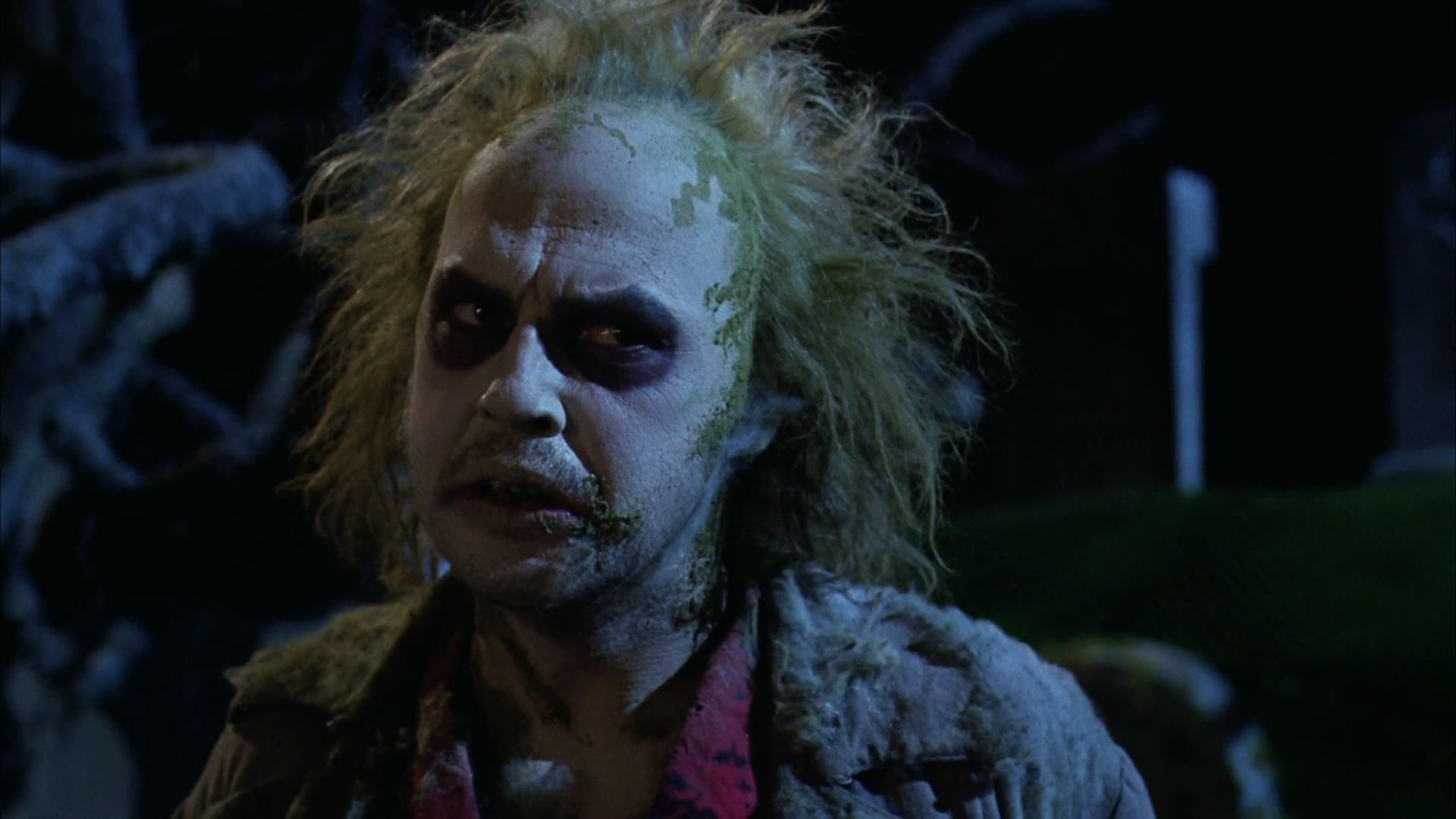 HD PC desktop wallpaper background featuring Beetlejuice from the movie — pale, wild-haired specter with dark smeared eyes and a tattered suit against a shadowy night scene.