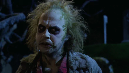 HD PC desktop wallpaper background featuring Beetlejuice from the movie — pale, wild-haired specter with dark smeared eyes and a tattered suit against a shadowy night scene.