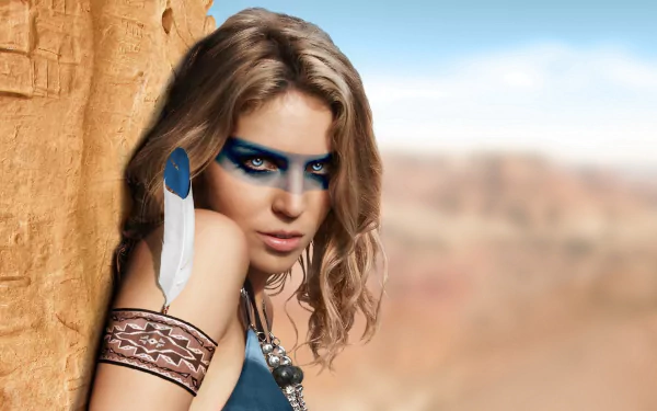 HD desktop wallpaper featuring a woman with Native American-inspired accessories and blue face paint, standing against a rocky background with a blurred, natural landscape in the distance.